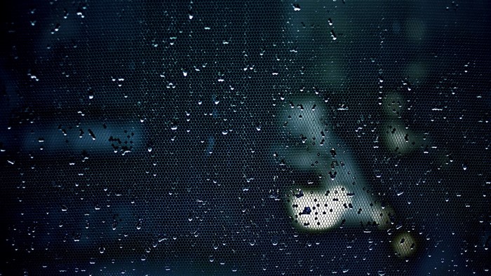 Water drops on a dark textured surface with blurred lights