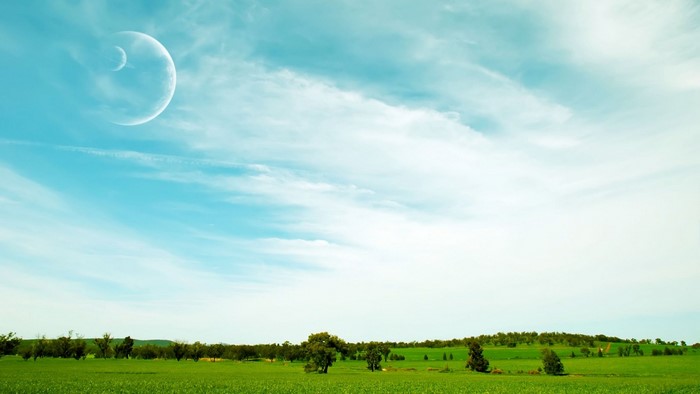 Two moons in a cloudy sky over a green field
