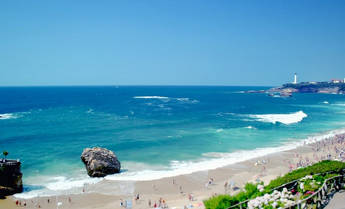 Beach with lighthouse and large rock in the ocean