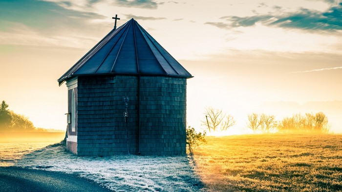 Small chapel in a misty field at sunrise