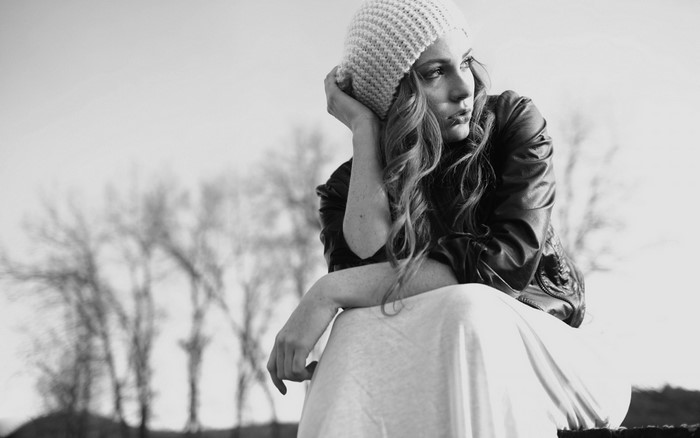 Woman in beanie and leather jacket looking away