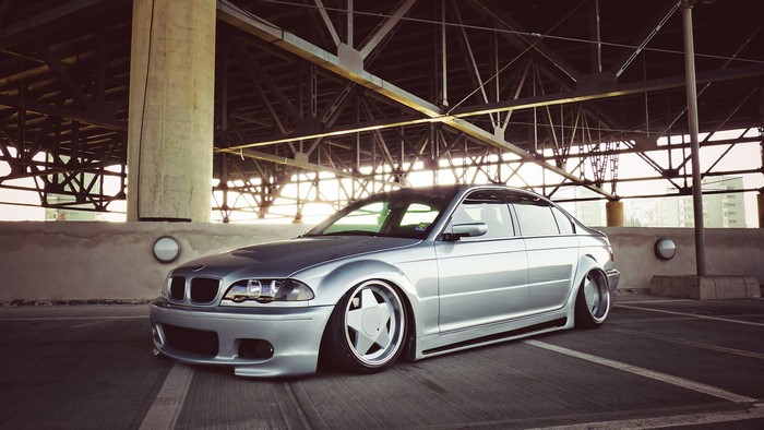 Silver BMW E46 Sedan with custom wheels parked under a bridge