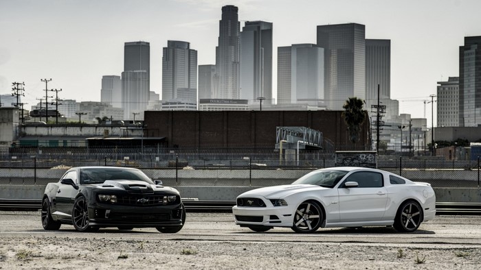 Black Chevrolet Camaro and White Ford Mustang in City