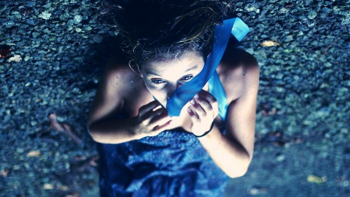 Girl with blue ribbon covering mouth