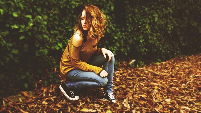 Woman with auburn hair squatting outdoors in autumn