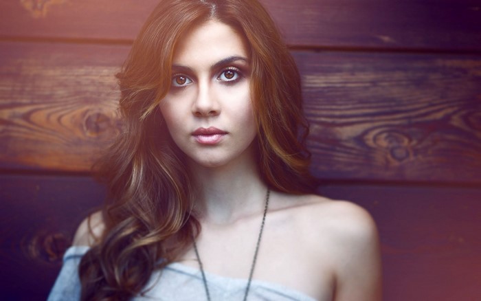 Woman with long brown hair in a grey off-the-shoulder top