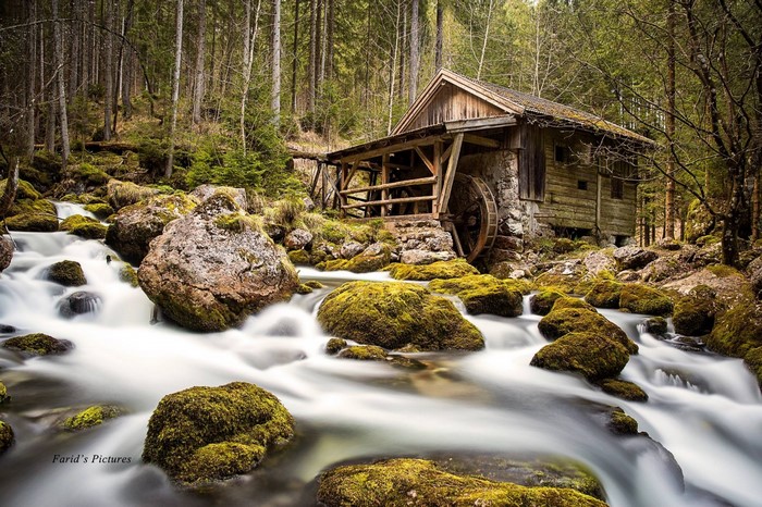 Old watermill by a stream in a forest