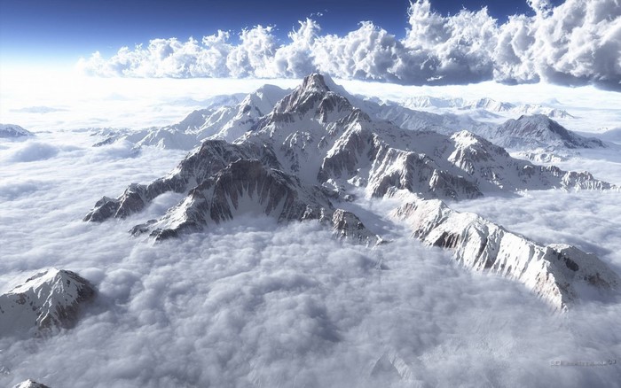 Snow-capped mountains above clouds under a blue sky