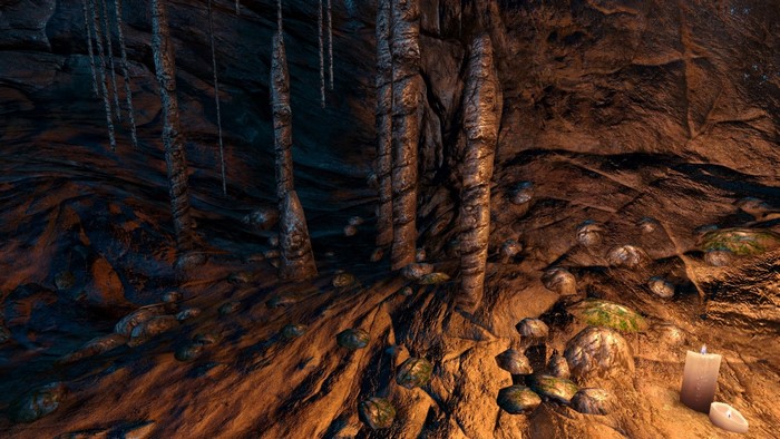 Cave interior with stalactites and a lit candle