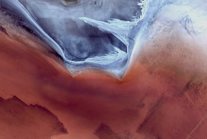 Aerial view of salt flats with red and blue hues