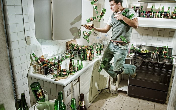 Man jumping in a kitchen with falling beer bottles