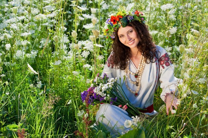 Woman with flower wreath in a field of wildflowers