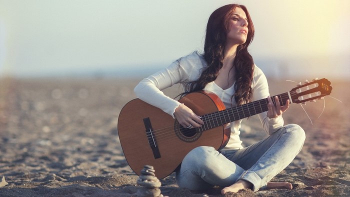 Woman playing guitar on a beach