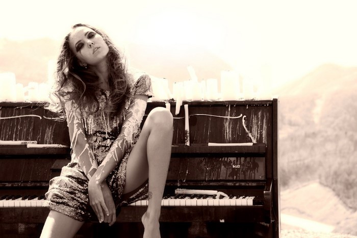 Woman sitting on a piano with white paint