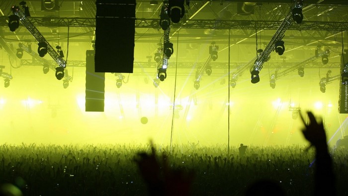 Concert crowd with yellow stage lights and speakers
