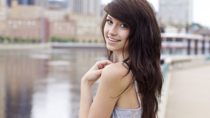 Woman with long brown hair smiling outdoors