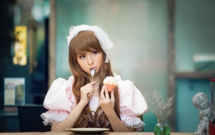 Woman in pink dress eating a cupcake