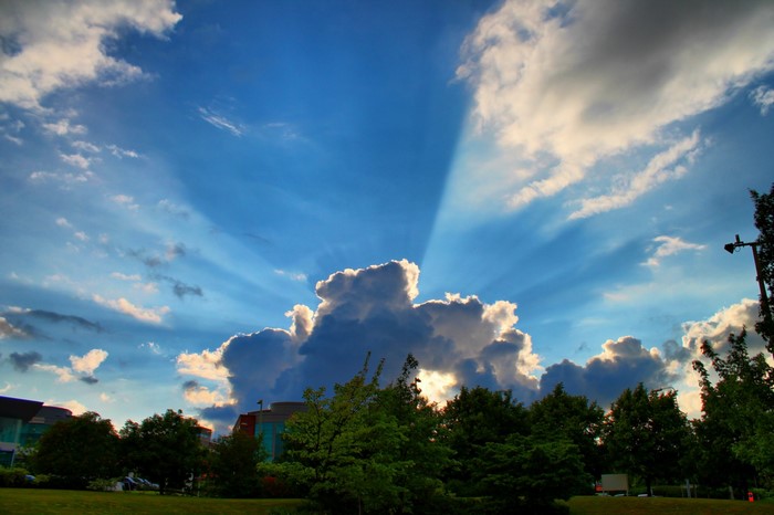 Sunbeams through clouds over trees and buildings