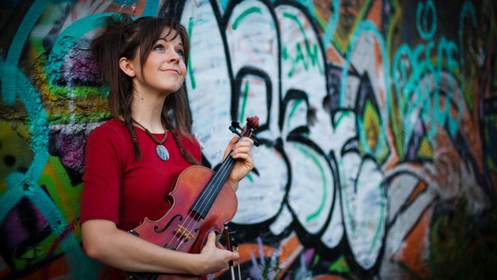 Woman with violin in front of graffiti wall