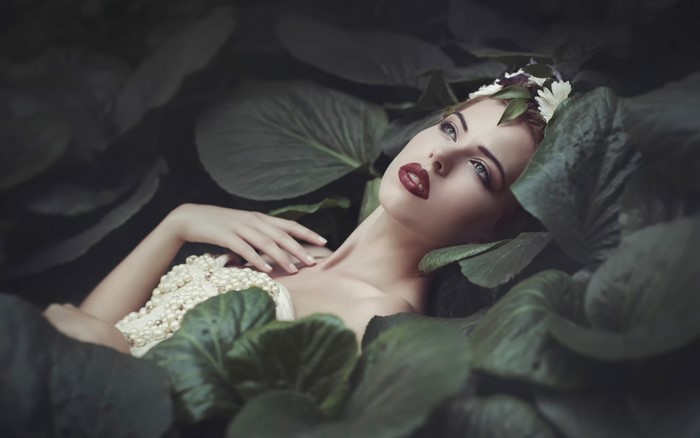 Woman with flower crown lying among lily pads