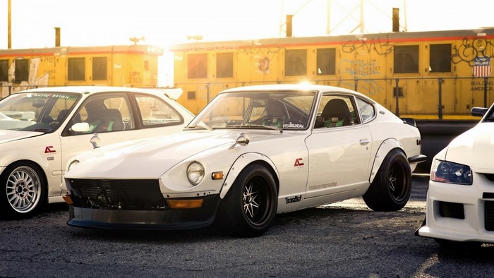 White Nissan Fairlady Z cars parked near a yellow train