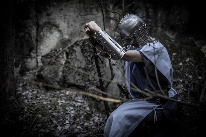 Knight in armor kneeling in forest