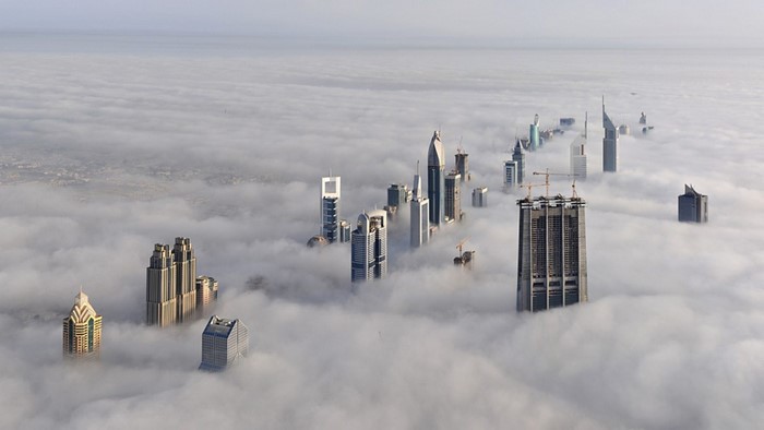Dubai skyscrapers emerging from clouds aerial view