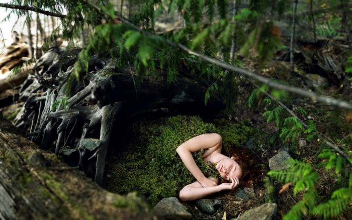 Redhead woman lying on moss in a forest