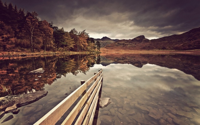 Wooden pier on a lake with autumn trees and mountains