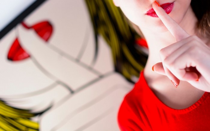 Woman with finger on lips in front of pop art