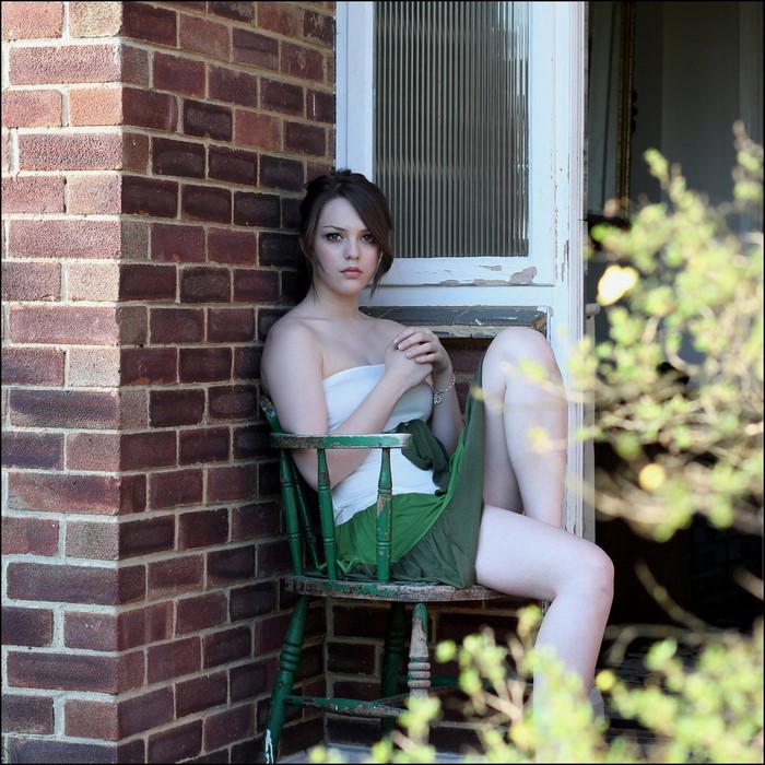 Young Woman Sitting Calmly by Brick Wall