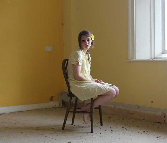 Woman with yellow flower in hair sitting in yellow room