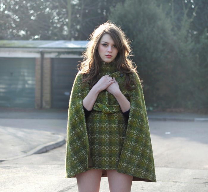 Woman wearing a green patterned cape outdoors