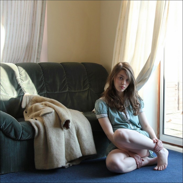 Young Woman Sitting Near Window on Blue Carpet