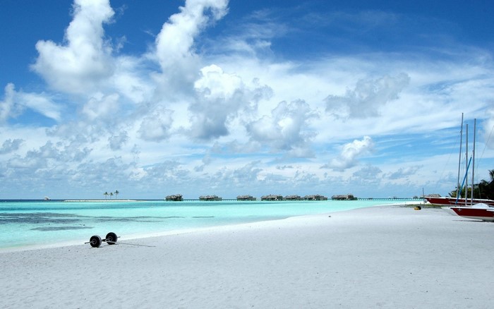 Beach with overwater bungalows and sailboats