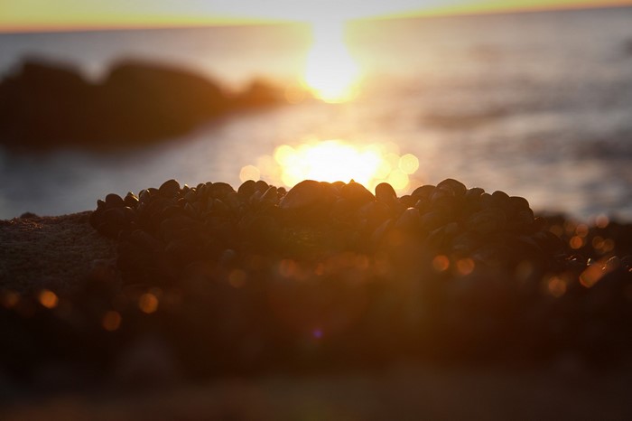 Sunset over the sea with rocks in the foreground