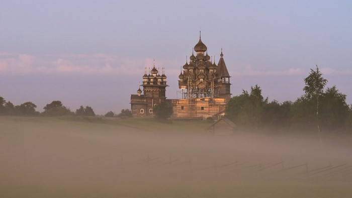 Wooden churches in fog at sunrise