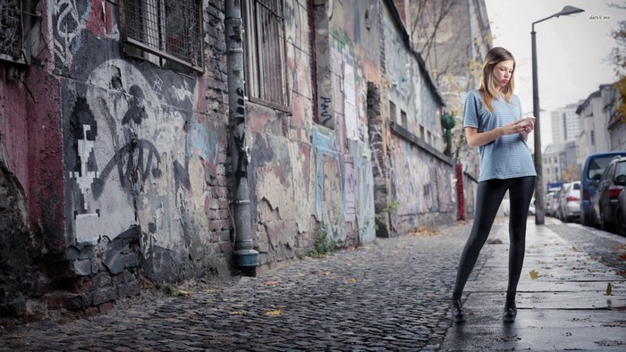 Woman looking at phone on graffiti-covered street