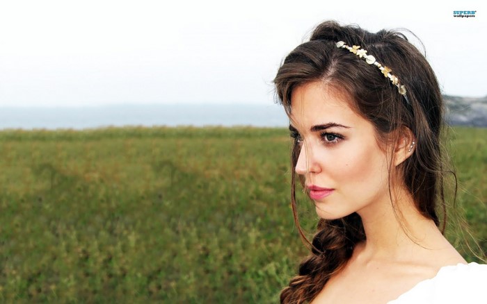 Woman with brown hair and headband in a field