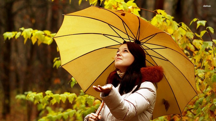 Woman holding a yellow umbrella in autumn