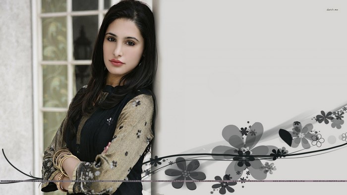 Nargis Fakhri leaning against a wall with floral design