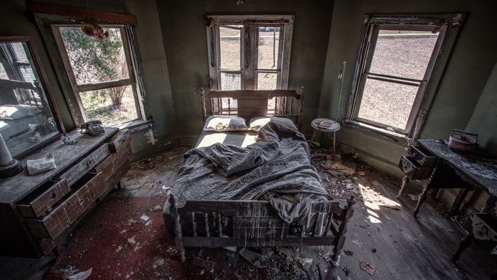 Abandoned bedroom with bed and dresser