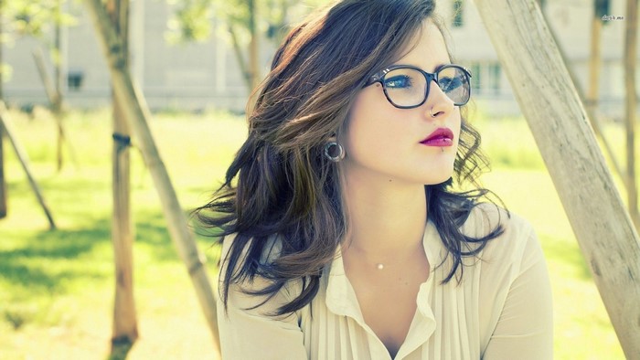 Woman with glasses and dark hair wearing a white shirt