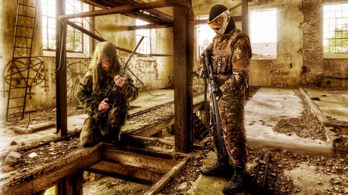 Two soldiers in camouflage gear with rifles in abandoned building