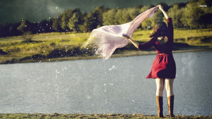 Woman in red dress holding scarf by lake