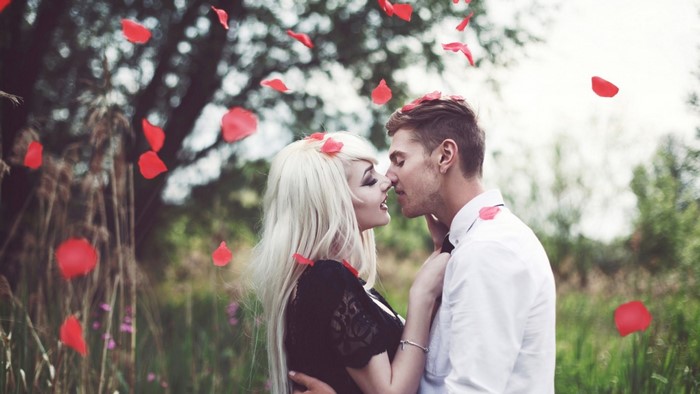Couple kissing with rose petals falling