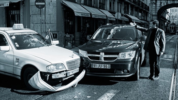 Man gestures at damaged Mercedes taxi and Dodge SUV after crash