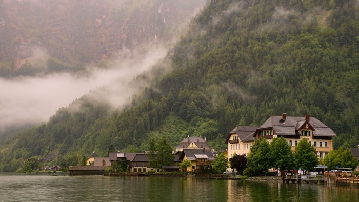 Village on a lake at the foot of a misty mountain
