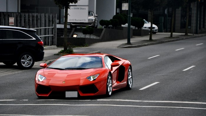 Red Lamborghini Aventador driving on a city street