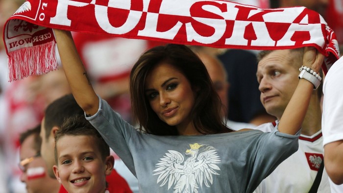 Woman holding Polish flag scarf with child and man